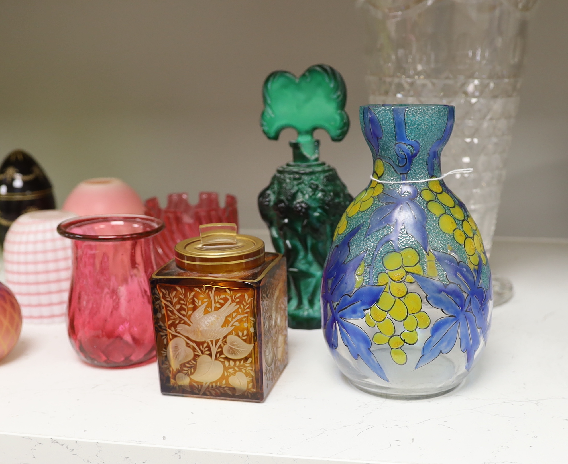 A quantity of various coloured and clear glass including an Art Deco figural scent bottle, cranberry glass vases and a yellow glass jar and cover, largest 30cm high